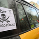 A placard reading “Uber public enemy” hangs from the window of a taxi on March 18, 2021 in Barcelona during a strike by taxis drivers organised against the ride-sharing service Uber.